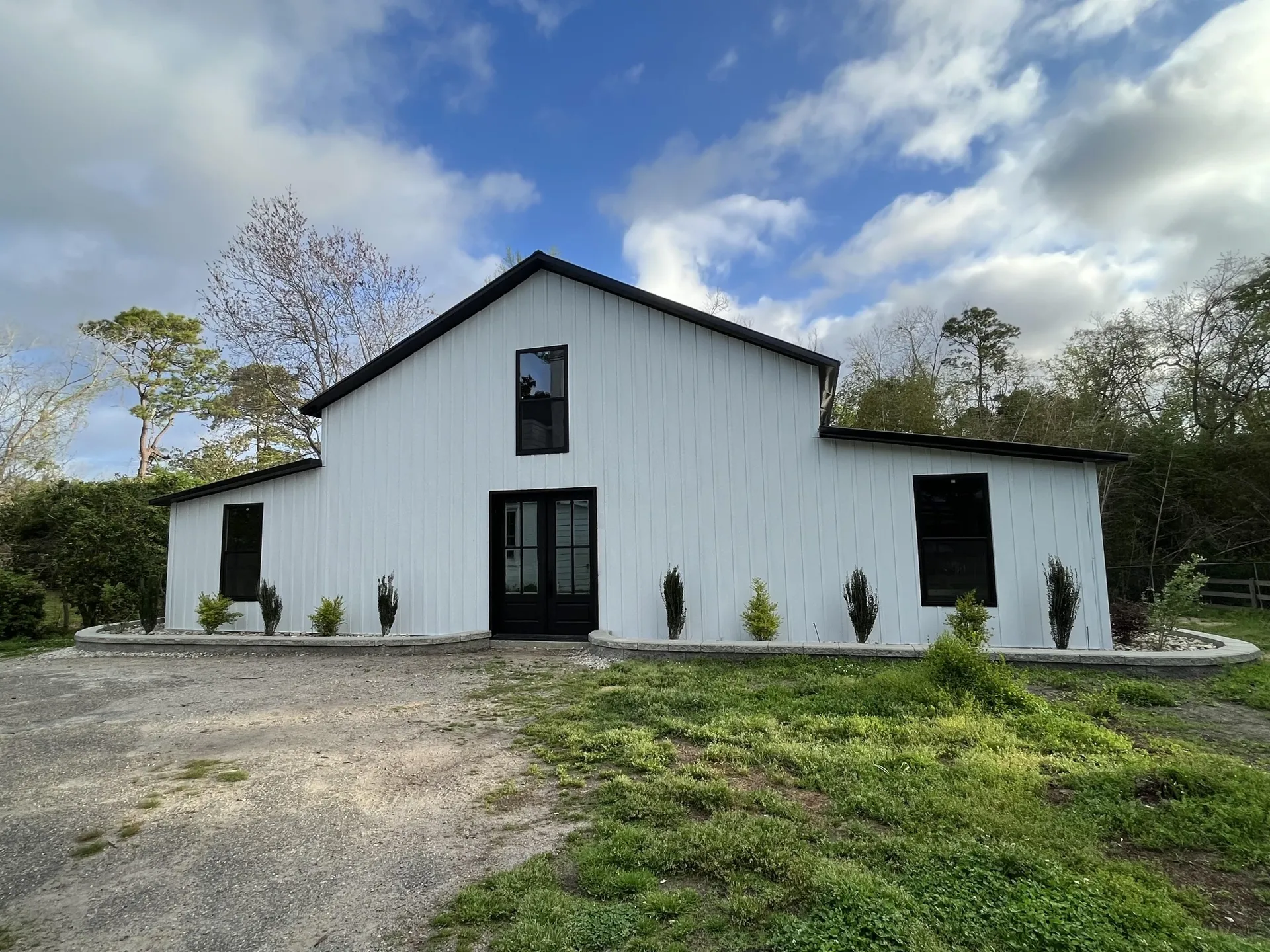 Modern white barndominium with black trim and landscaped grounds, built by METCO